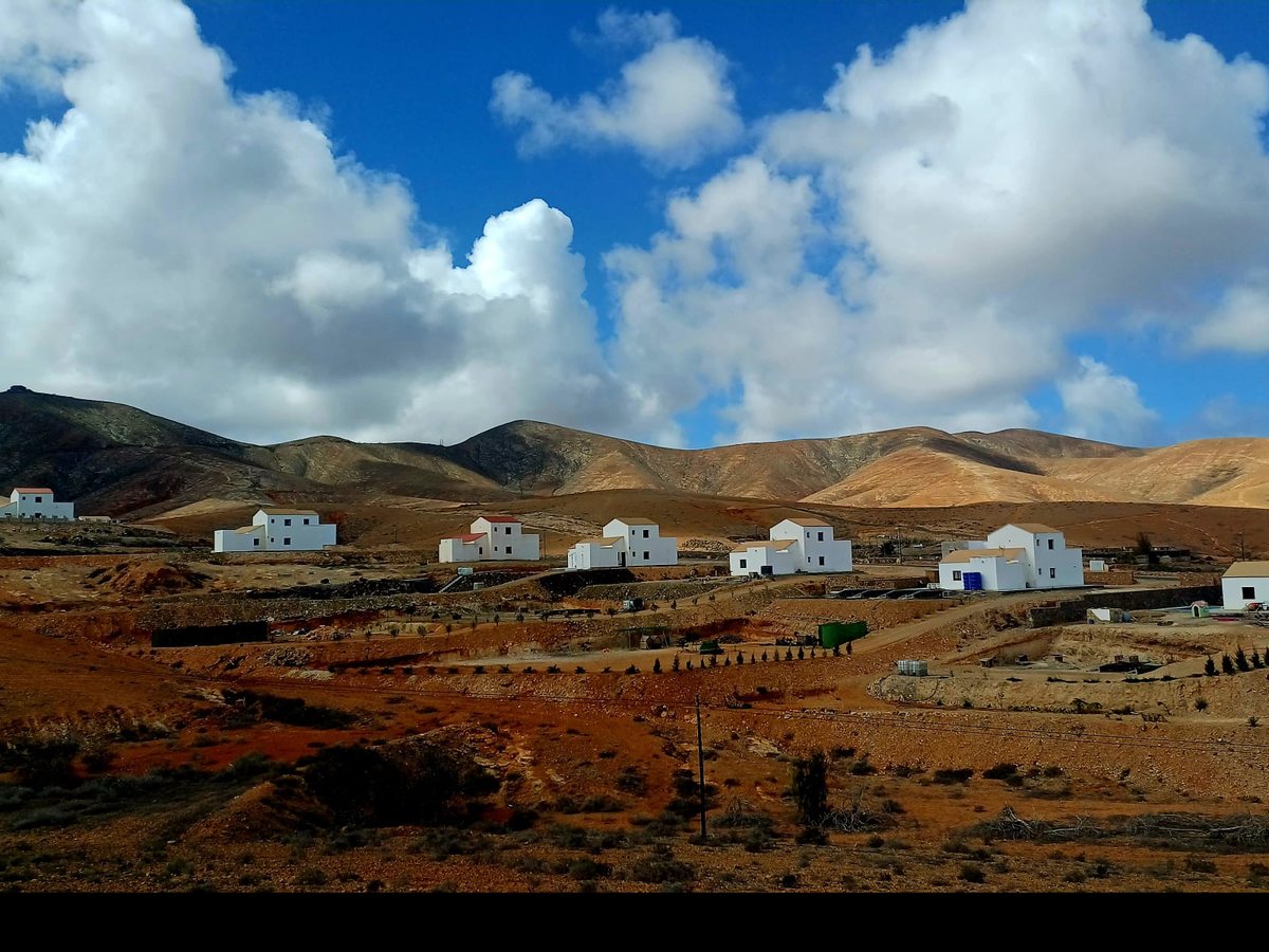 Bílé domky pod sopečnými kopci na Fuerteventuře, modré nebe s kupovými mraky